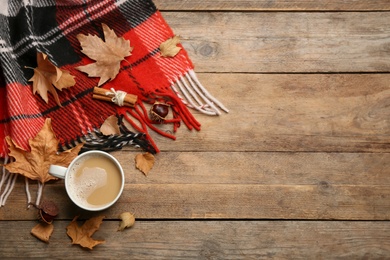 Flat lay composition with coffee and warm plaid on wooden table, space for text