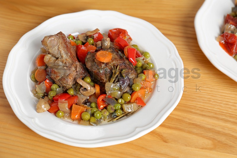 Plate with meat and garnish prepared in multi cooker on wooden table