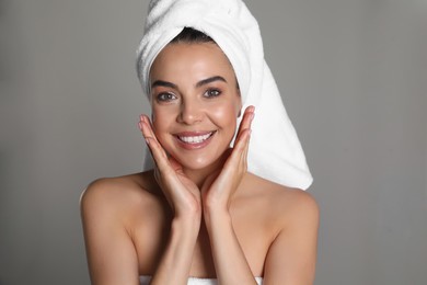 Beautiful young woman with towel on head against grey background