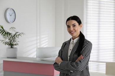 Portrait of receptionist near countertop in office, space for text