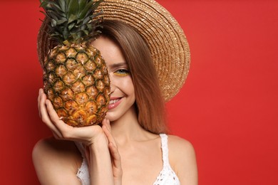 Photo of Young woman with fresh pineapple on red background, space for text. Exotic fruit
