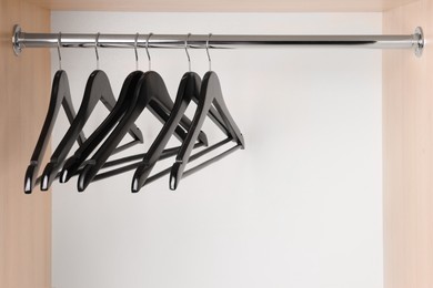 Set of black clothes hangers on wardrobe rail. Space for text