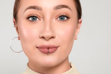 Young woman with lip piercing on white background, closeup