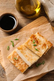 Delicious turnip cake with green onion and soy sauce on wooden table, flat lay