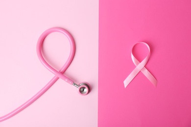 Photo of Pink ribbon and stethoscope on color background, top view. Breast cancer concept