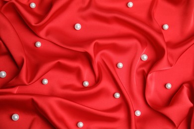 Many beautiful pearls on delicate red silk, top view