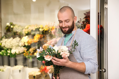 Professional florist with bouquet of fresh flowers in shop