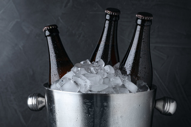 Photo of Metal bucket with beer and ice cubes on black background, closeup