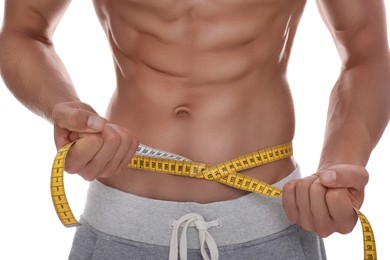 Shirtless man with slim body and measuring tape around his waist on white background, closeup