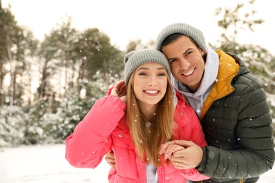 Beautiful happy couple in snowy forest on winter day