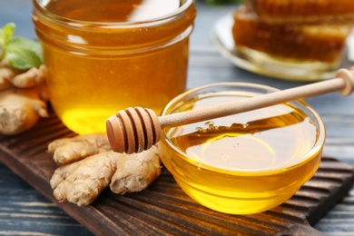 Photo of Honey and ginger on blue wooden table, closeup. Natural cold remedies