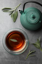 Photo of Aromatic herbal tea with sage on grey table, flat lay