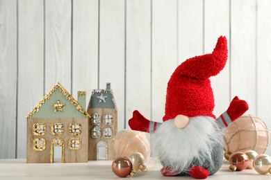 Cute Christmas gnome and festive decor on table against white wooden background, space for text
