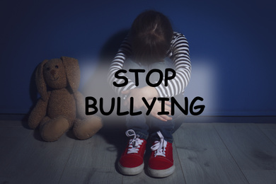 Message STOP BULLYING and abused little girl crying near blue wall