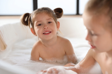 Cute little sisters taking bubble bath together