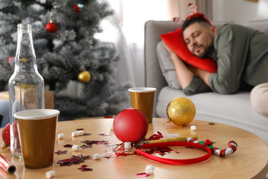 Man sleeping after New Year party, focus on messy table