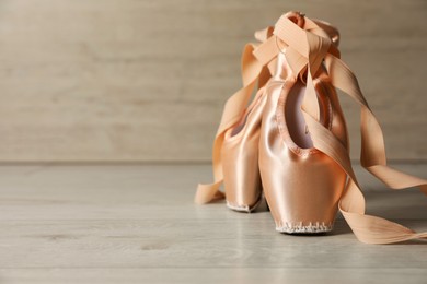 Photo of Ballet shoes. Elegant pointes on wooden floor indoors, space for text