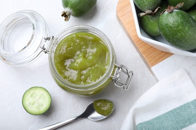 Feijoa jam and fresh fruits on light grey table, flat lay