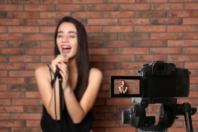 Music teacher recording singing lesson near brick wall