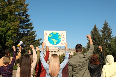 Group of people with posters protesting against climate change outdoors, back view
