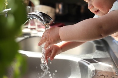 Little child washing hands in kitchen, closeup view