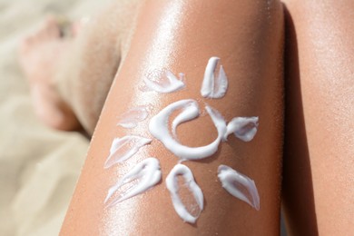 Sun drawn with sunscreen on woman's leg at beach, closeup
