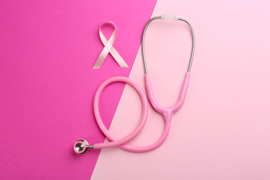 Pink ribbon as breast cancer awareness symbol and stethoscope on color background, flat lay