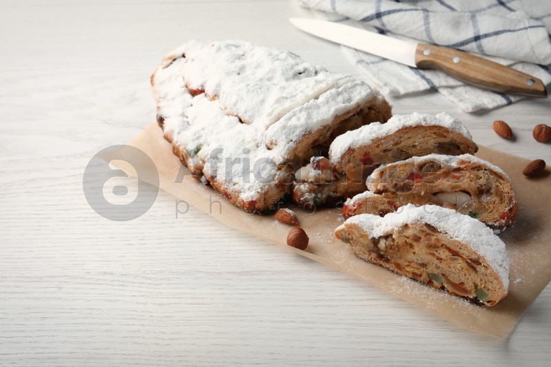 Traditional Christmas Stollen with icing sugar on white wooden table, space for text