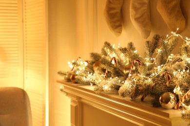 Beautiful decoration of fir tree branches, candy canes, fairy lights and Christmas balls in room, closeup