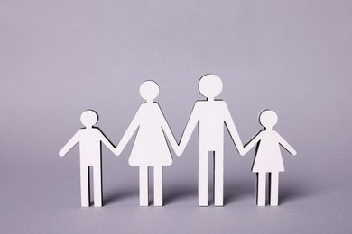 Figures of family stainding on lilac background. Insurance concept