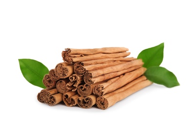 Aromatic dry cinnamon sticks and green leaves on white background