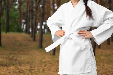 Cute little girl in kimono in forest, closeup. Karate practicing