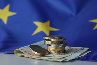 Coins, banknotes and European Union flag on table, closeup