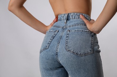 Woman in stylish jeans on light background, closeup