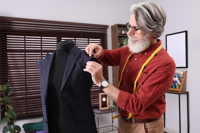 Professional tailor working with mannequin in atelier