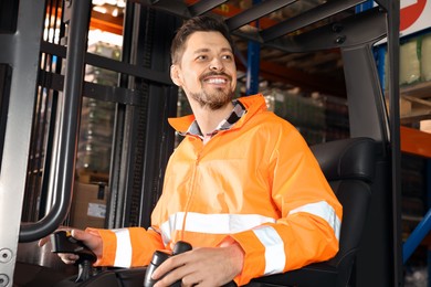 Photo of Happy worker sitting in forklift truck at warehouse