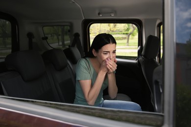 Young woman suffering from nausea in car