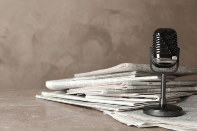 Newspapers and vintage microphone on marble table. Journalist's work