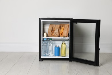 Mini bar filled with food and drinks near white wall indoors