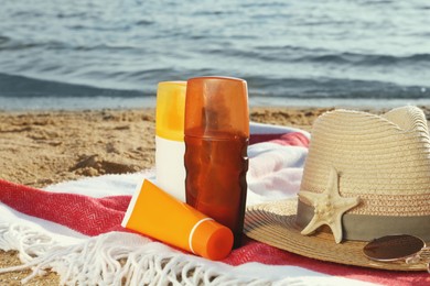 Photo of Sun protection products and beach accessories on blanket near sea