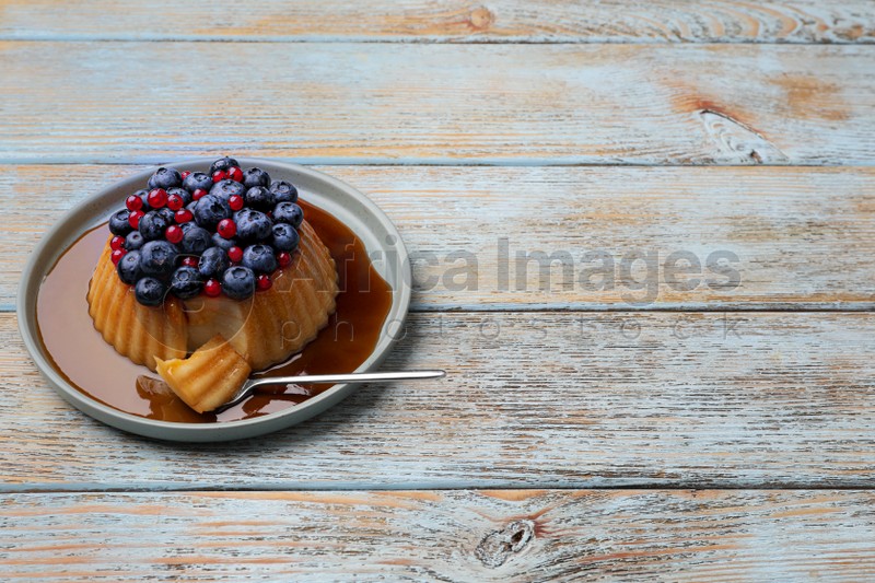 Delicious pudding with caramel, blueberries and redcurrants on wooden table. Space for text