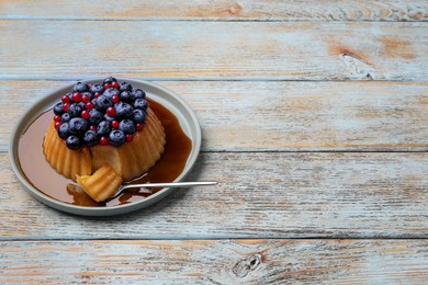 Photo of Delicious pudding with caramel, blueberries and redcurrants on wooden table. Space for text