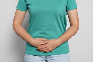 Young woman suffering from menstrual pain on grey background, closeup