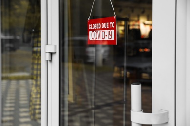 Red sign with words "Closed Covid-19" hanging on glass door