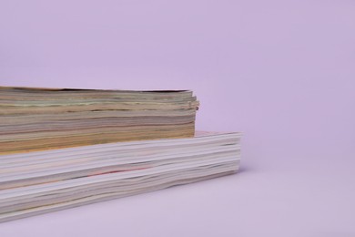 Photo of Many stacked magazines on violet background, closeup. Space for text