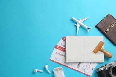 Flat lay composition with passports, stamp and flight tickets on light blue background, space for text