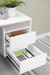 Photo of Office supplies in open desk drawers indoors