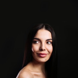 Photo of Portrait of happy young woman with beautiful black hair and charming smile on dark background, space for text