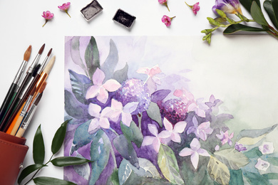 Flat lay composition with watercolor paints and floral picture on white background