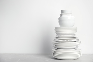 Stack of clean tableware on white table. Space for text